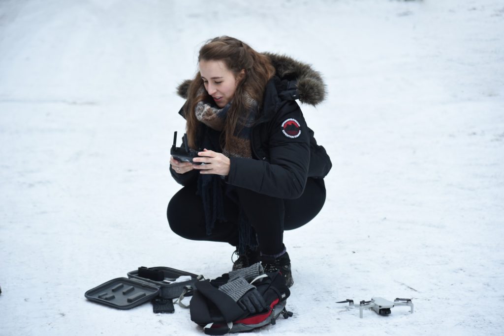 Erin squatting down to set up her drone for a snow landscape in Aberdeenshire