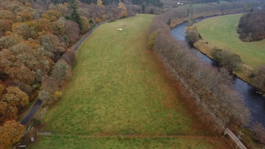 Arial Shot of a large rectangular shaped field surrounded by forest with the River Don on the right side